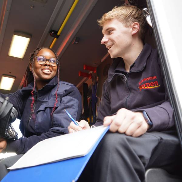 Das Foto zeigt eine junge Frau und einen jungen Mann in einem Feuerwehr-Fahrzeug.