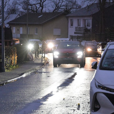 Auf der schmalen Straße parken Autos und verengen die Fahrbahn.