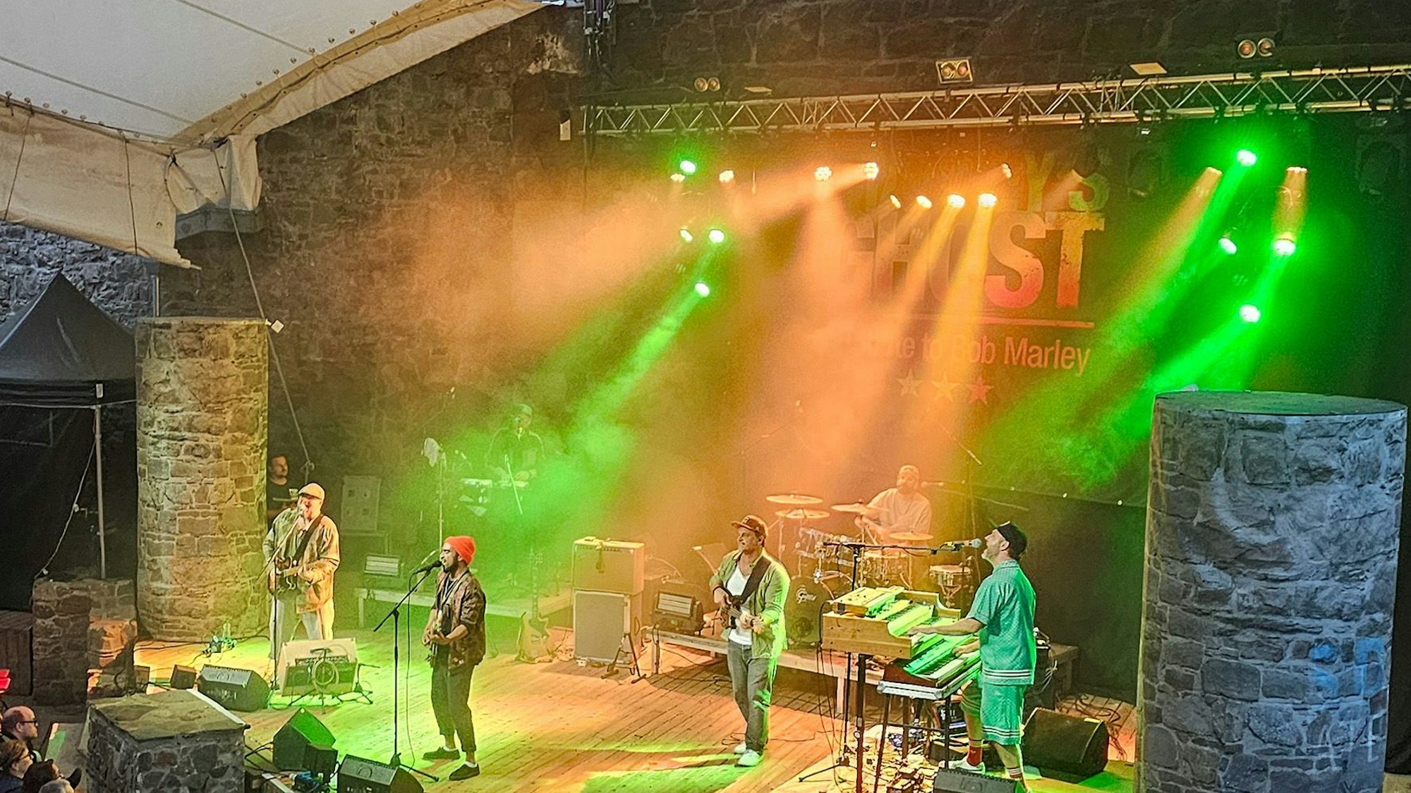 Die Band steht auf einer Bühne, die in grünes Licht getaucht ist.