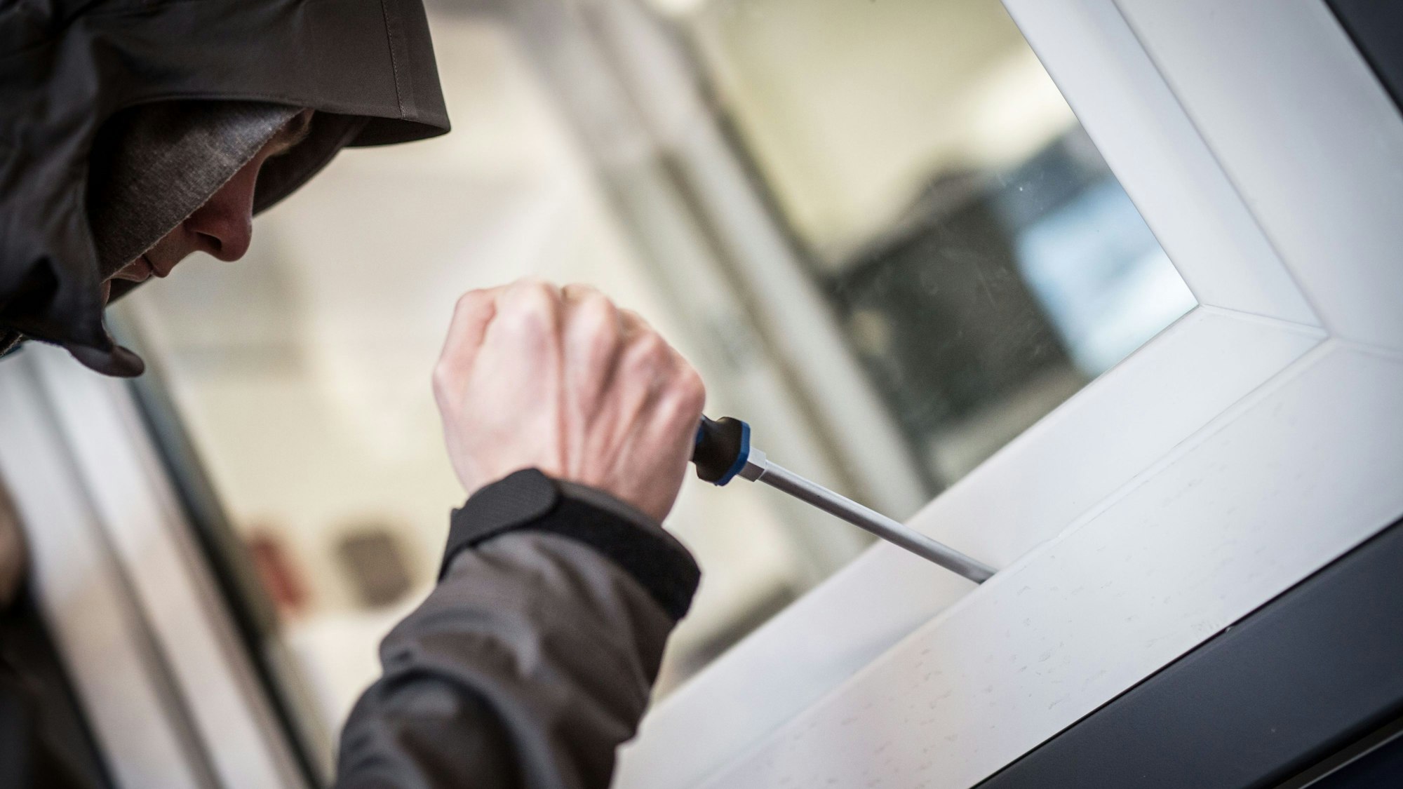 Ein Mann demonstriert, wie ein Fenster aufgehebelt werden kann (Symbolfoto).