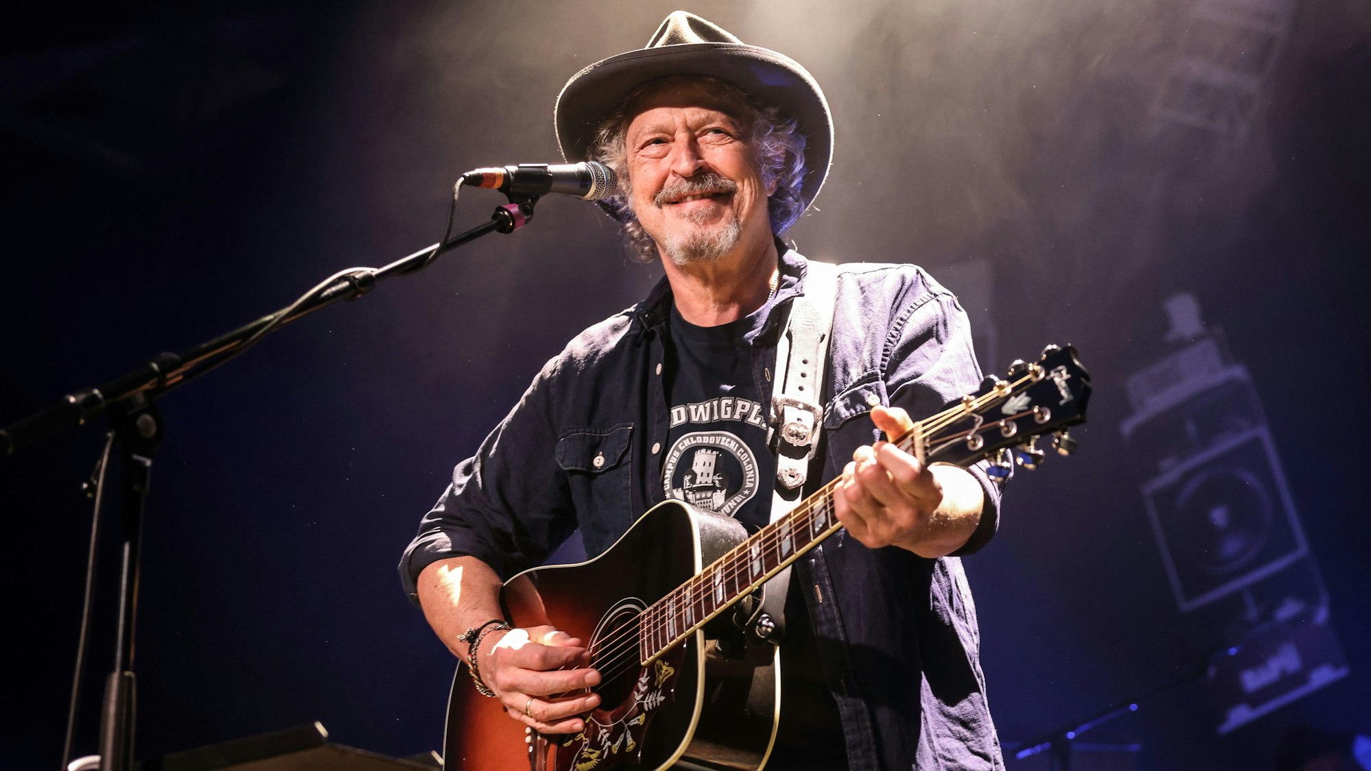 Wolfgang Niedecken steht mit einer Gitarre auf der Bühne.