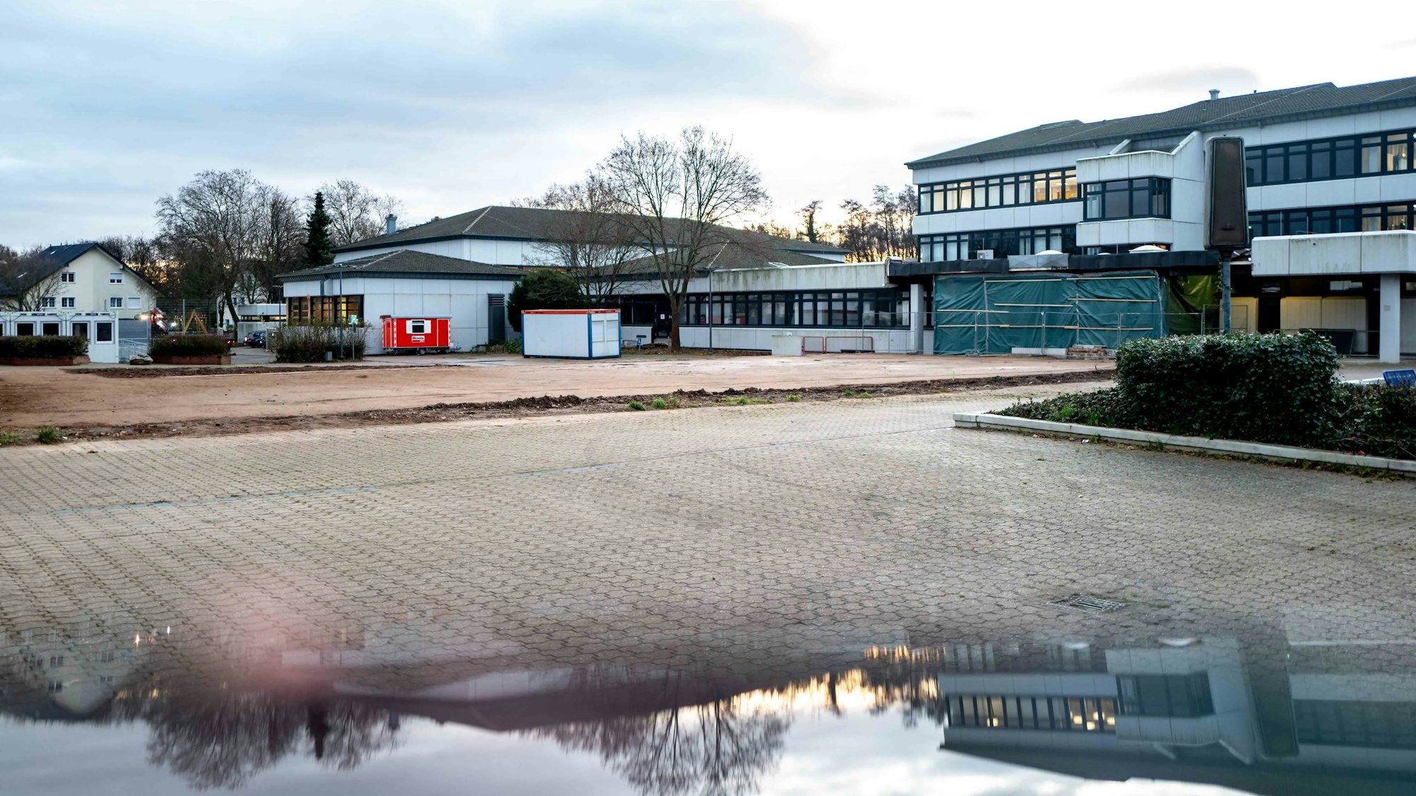 Blick auf das Thomas-Eßer-Berufkolleg in Euskirchen. Das Gebäude spiegelt sich in einer Pfütze auf dem Schulhof.
