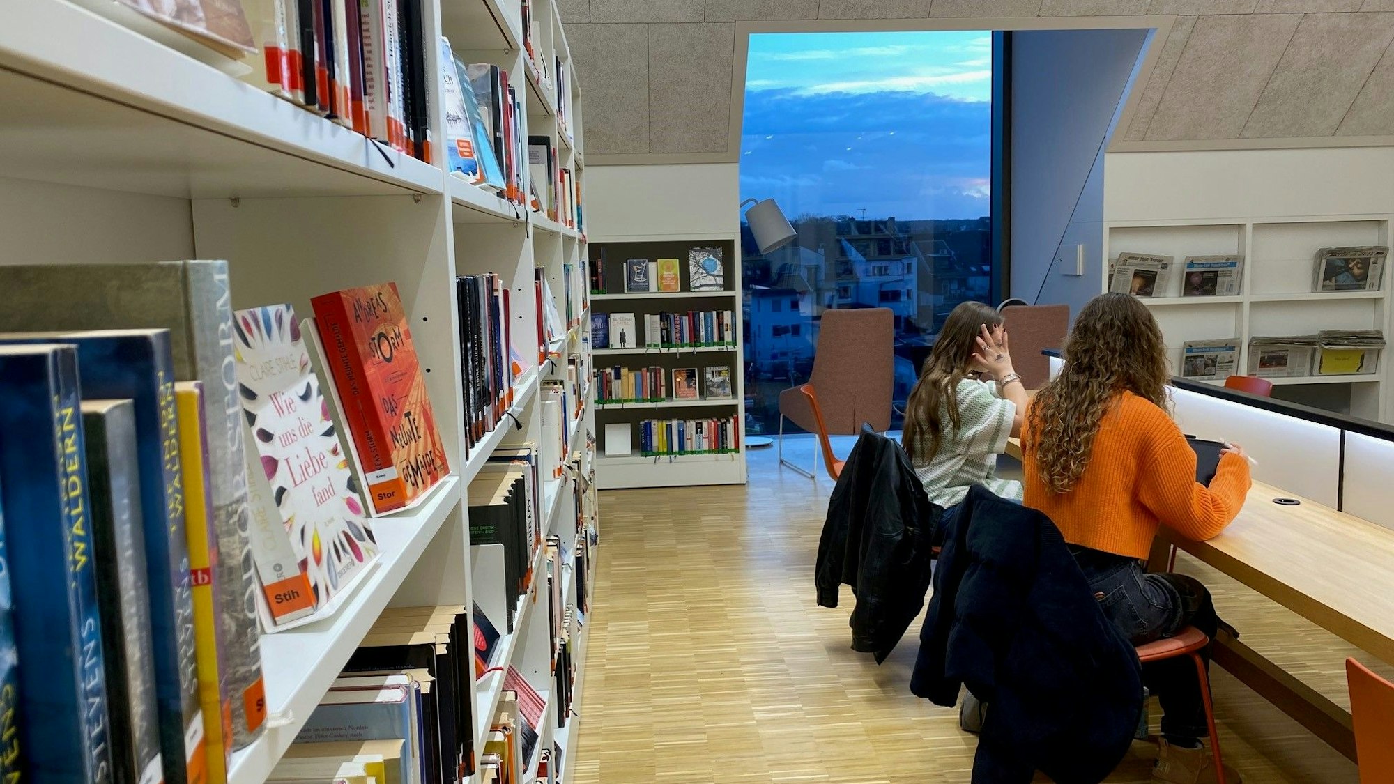 Zu sehen ist die obere Etage der Bibliothek, deren großes Fenster Blicke über die Stadt ermöglicht.