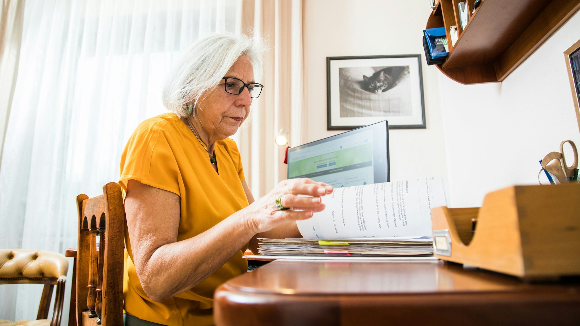 Eine Rentnerin sitzt an ihrem Schreibtisch und macht eine Steuererklärung mit dem Online-Portal Elster (gestellte Szene).