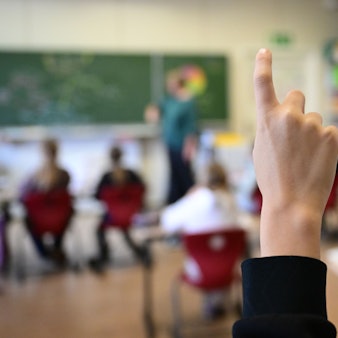 Schüler melden sich in einer vierten Klasse in einer Grundschule.