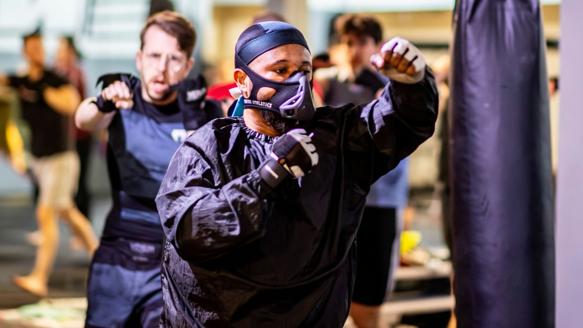 Das Bild zeigt den Kampfsportler Steavano Kojo Tuekpe, wie er durch das Trainingscenter läuft und dabei wie ein Boxer die Fäuste in die Luft schlägt.