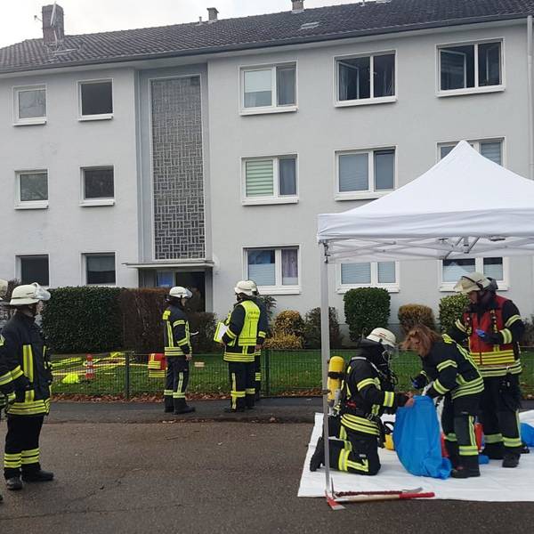Feuerwehrleute stehen vor einem Mehrfamilienhaus in Rösrath.