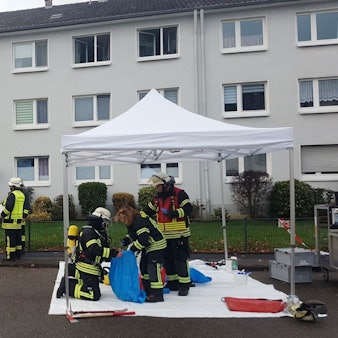 Feuerwehrleute stehen vor einem Mehrfamilienhaus in Rösrath.