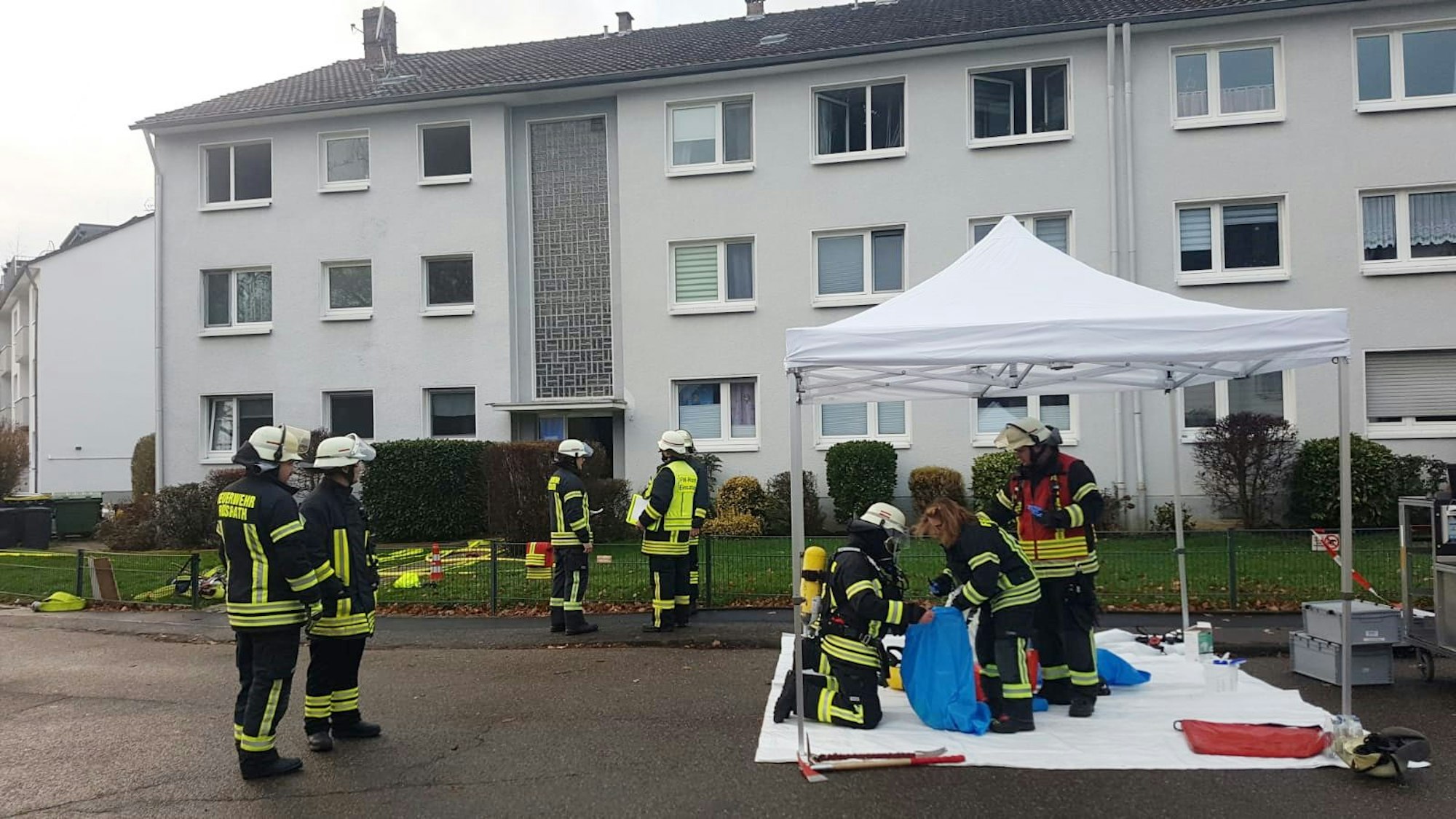 Feuerwehrleute stehen vor einem Mehrfamilienhaus in Rösrath.