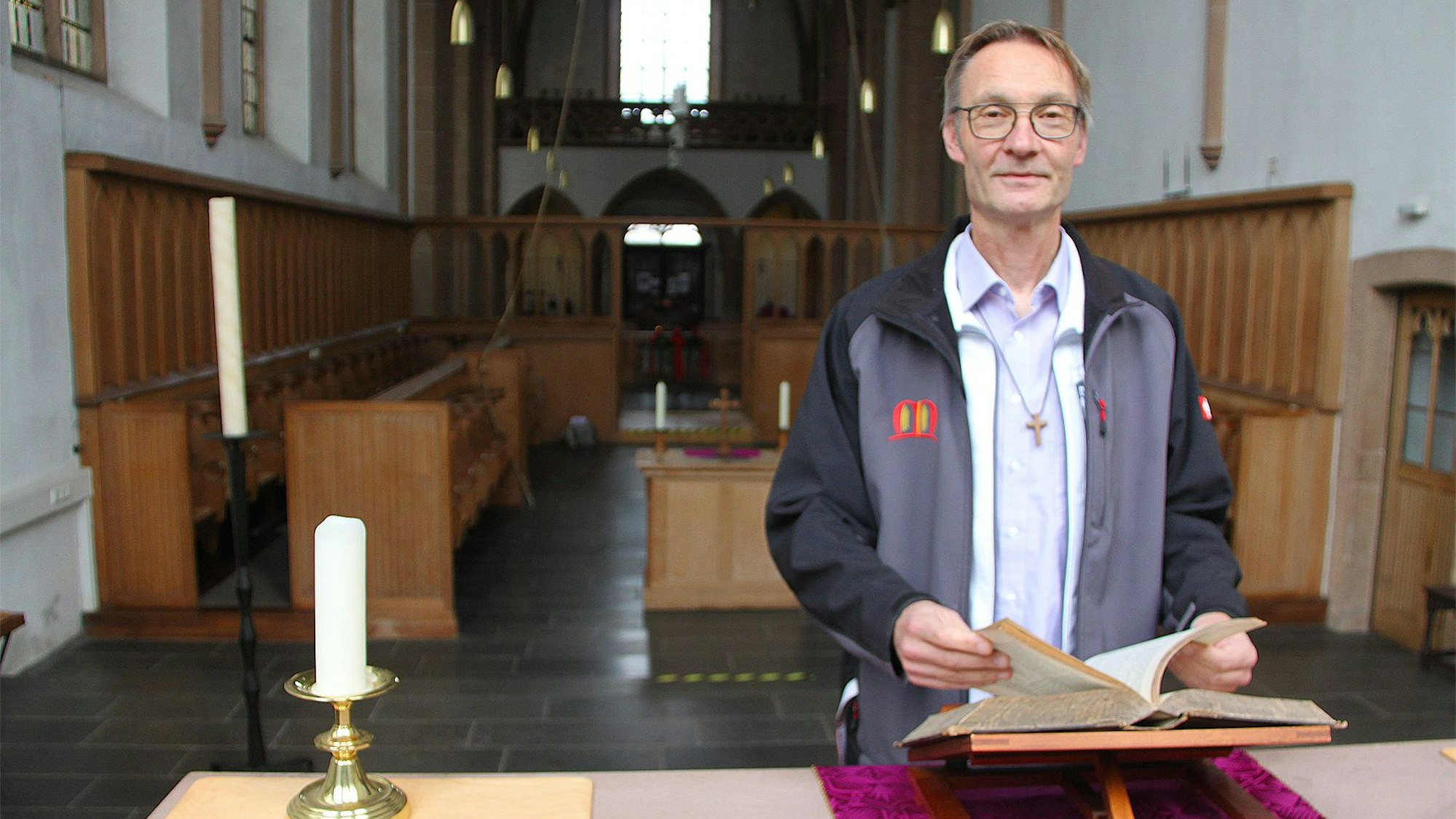Pfarrer Rose blättert am Altar in der Bibel.