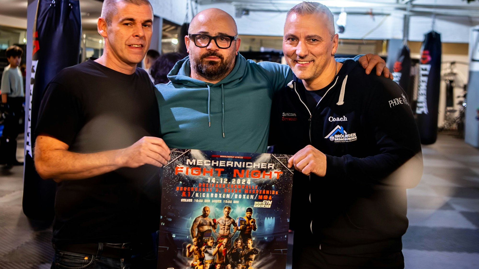 Das Bild zeigt Baker Barakat mit Thomas Brölingen und Frank Chelmowski. Sie halten das Veranstaltungsplakat in der Hand.