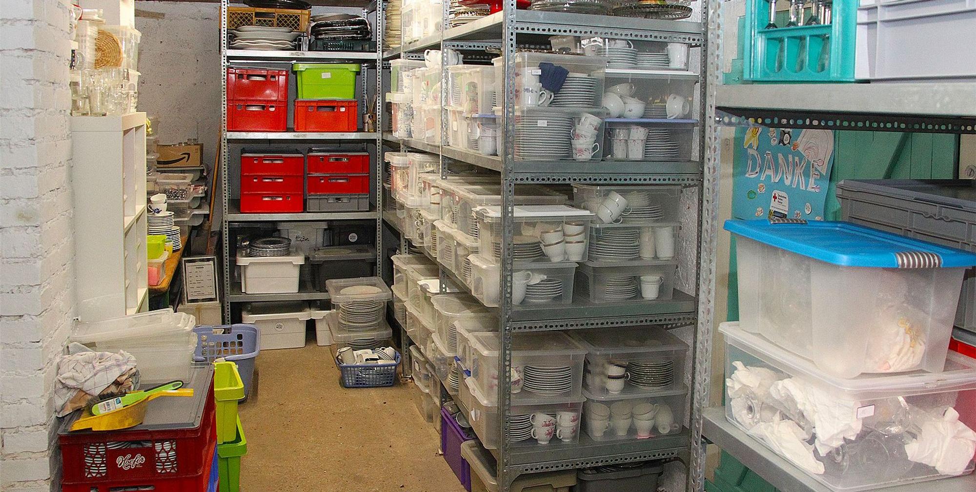 Das Foto zeigt Regale mit Geschirr und andere Utensilien, die in Transportkisten verpackt sind.