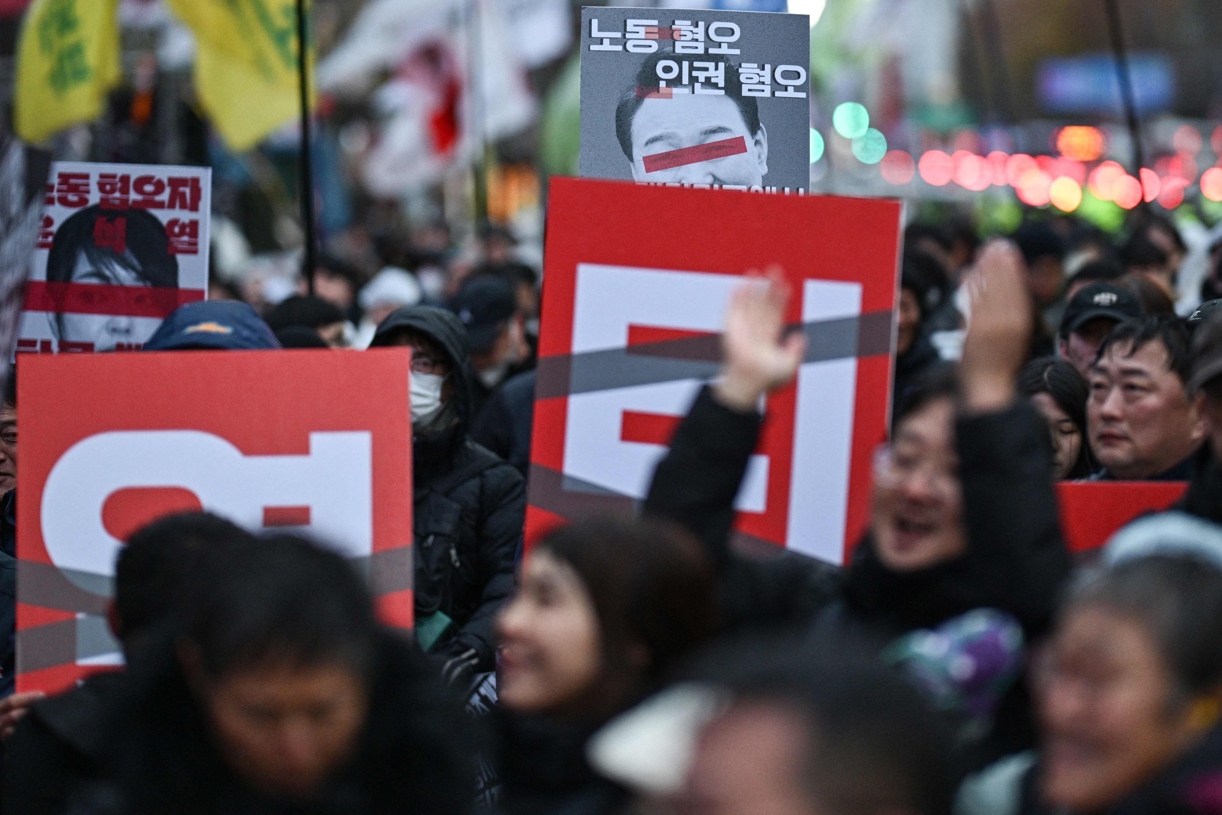 Demonstranten zeigen am 5. Dezember 2024 in Seoul Plakate mit dem Gesicht des südkoreanischen Präsidenten Yoon Suk Yeol.