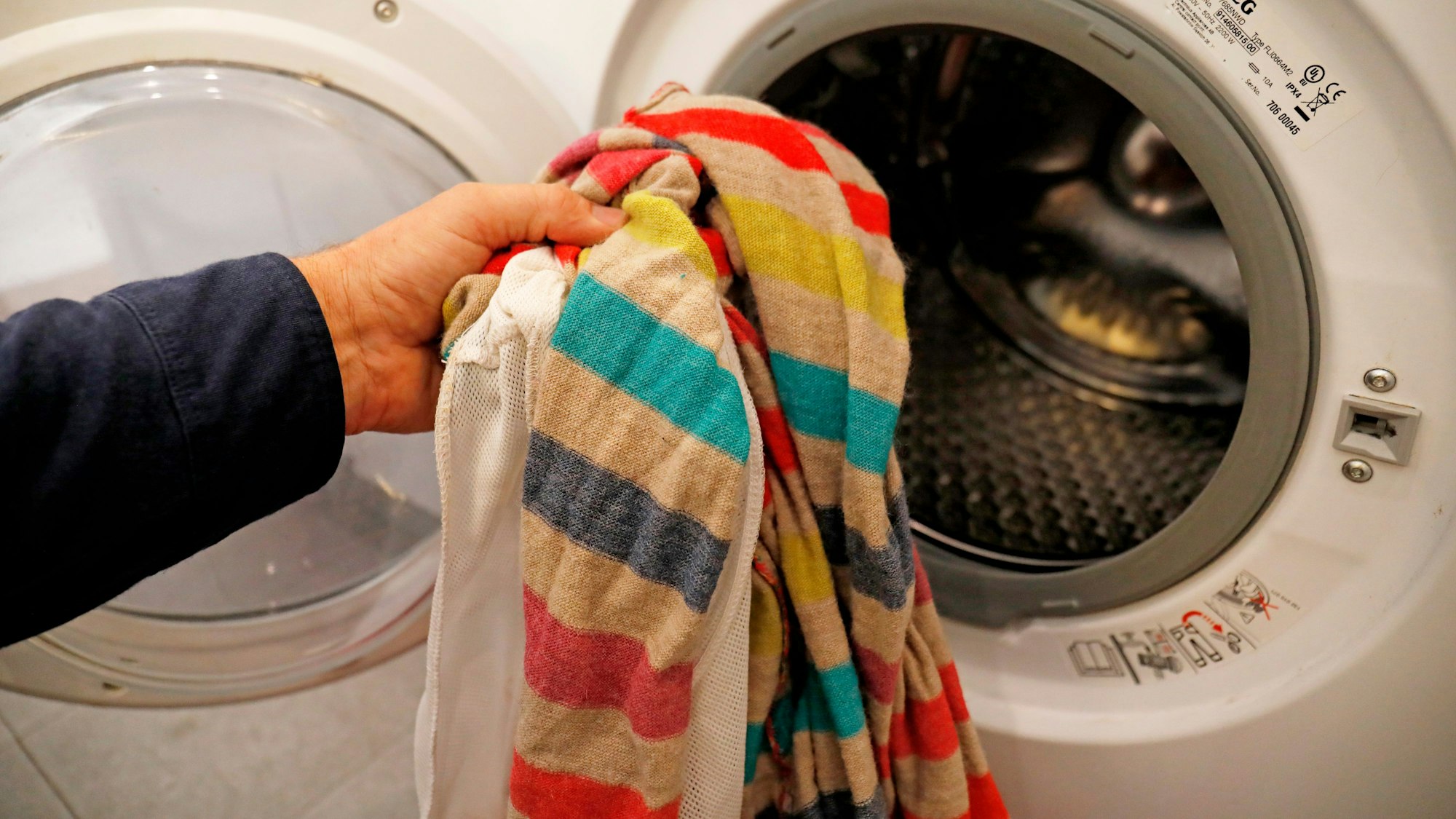 Ein Mann legt Kleidung in eine Waschmaschine.