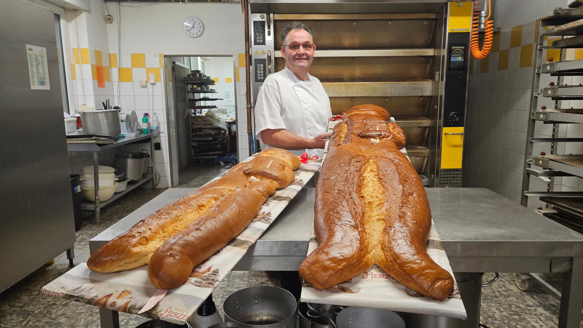 Zu sehen ist ein Bäcker in seiner Backstube mit übergroßen Weckmännern.