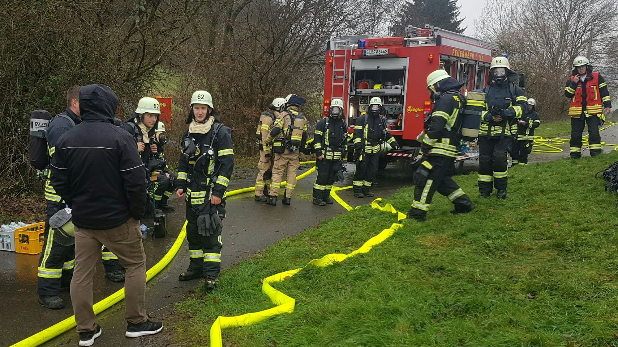 Feuerwehrleute stehen an einem Feuerwehrfahrzeug.