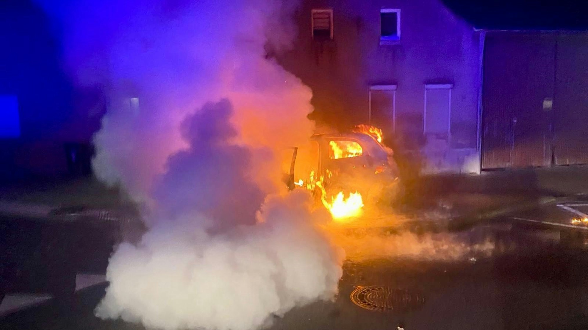 Ein Auto steht auf einer Straße in Flammen.