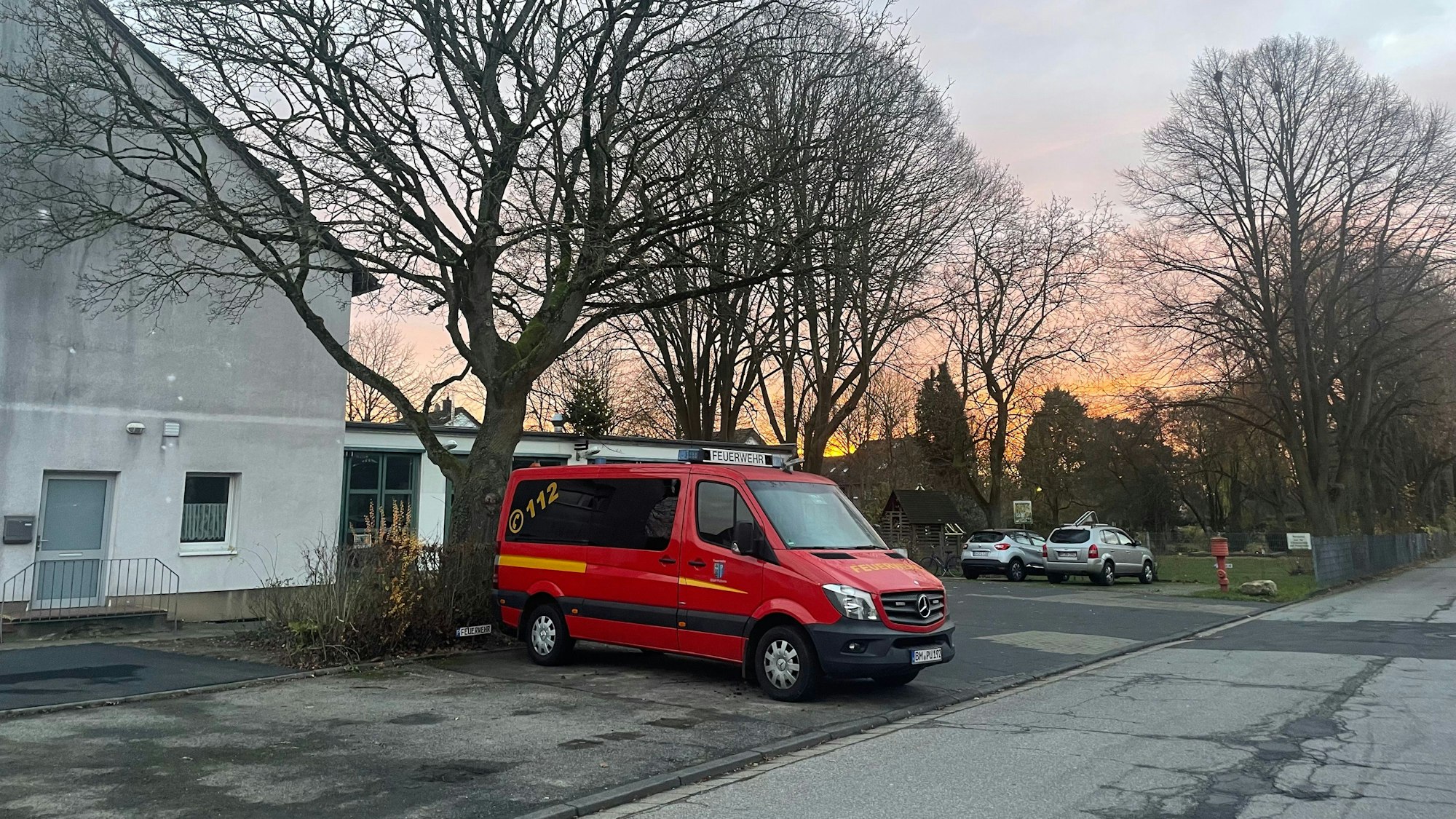 Im Hintergrund ein Gebäude mit heller Fassade, davor ein roter Transporter.