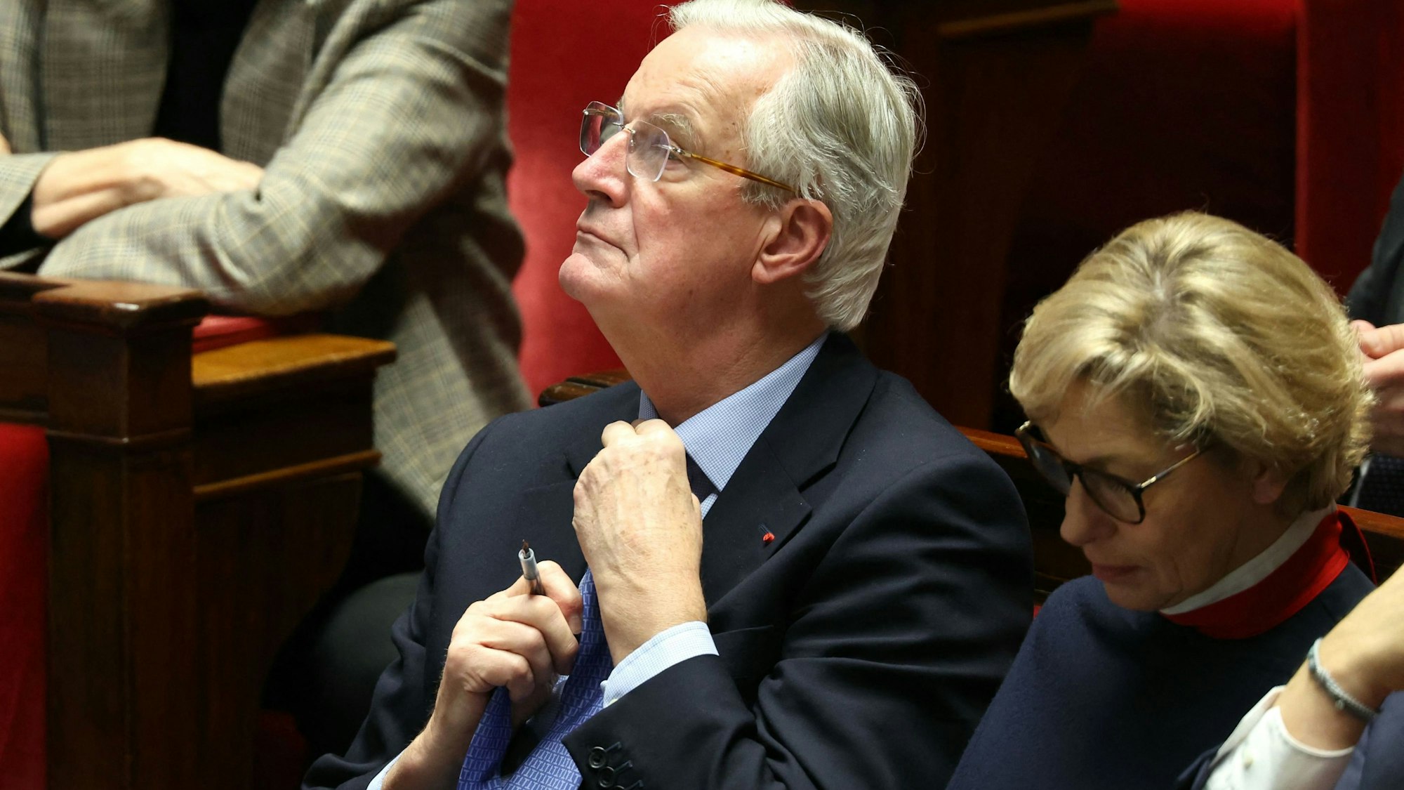 Der bisherige französische Premierminister Michel Barnier richtet seine Krawatte während der Debatte vor dem Misstrauensvotum gegen seine Regierung in der Nationalversammlung.