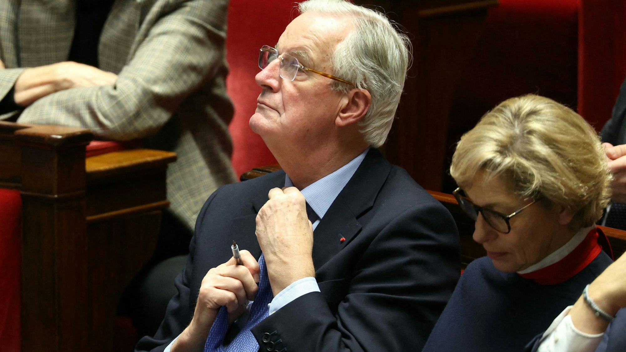 Der bisherige französische Premierminister Michel Barnier richtet seine Krawatte während der Debatte vor dem Misstrauensvotum gegen seine Regierung in der Nationalversammlung.