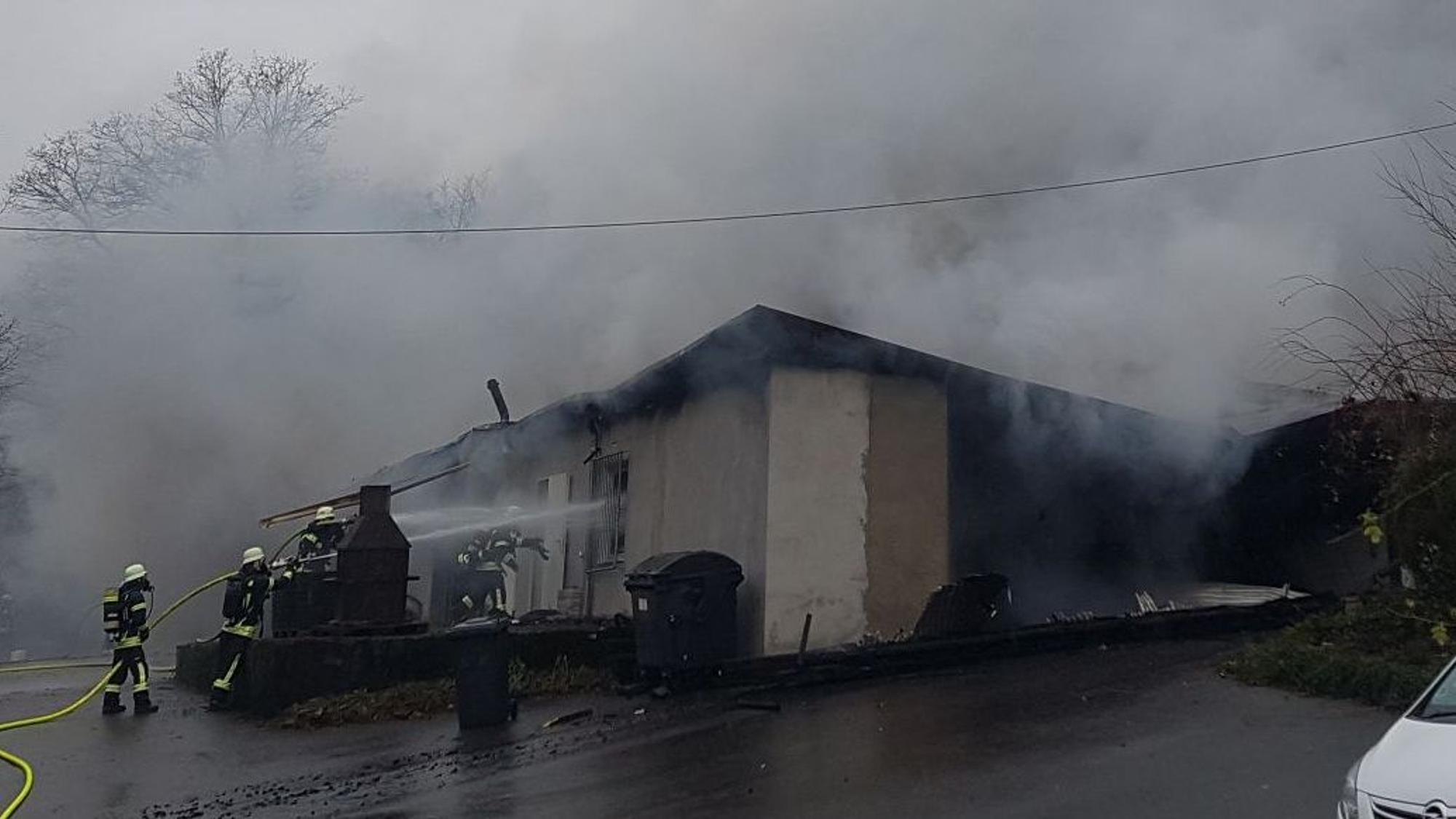 Feuerwehrleute lösche eine Lagerhalle aus der Rauch herausdringt.