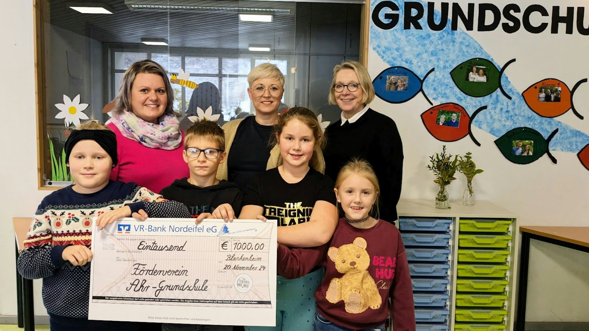 Alexandra Lüdke, Maren Benens und Kirsten Schäfer stehen nebeneinander. Davor stehen vier Kinder mit einem symbolischen Spendenscheck.