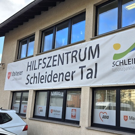 Blick auf das Hilfszentrum, an dem ein großes Transparent hängt.