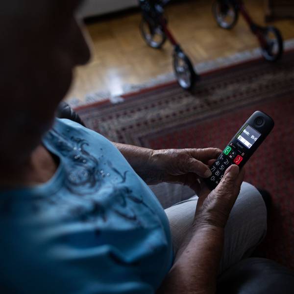 Eine Seniorin schaut auf ihr Telefon.