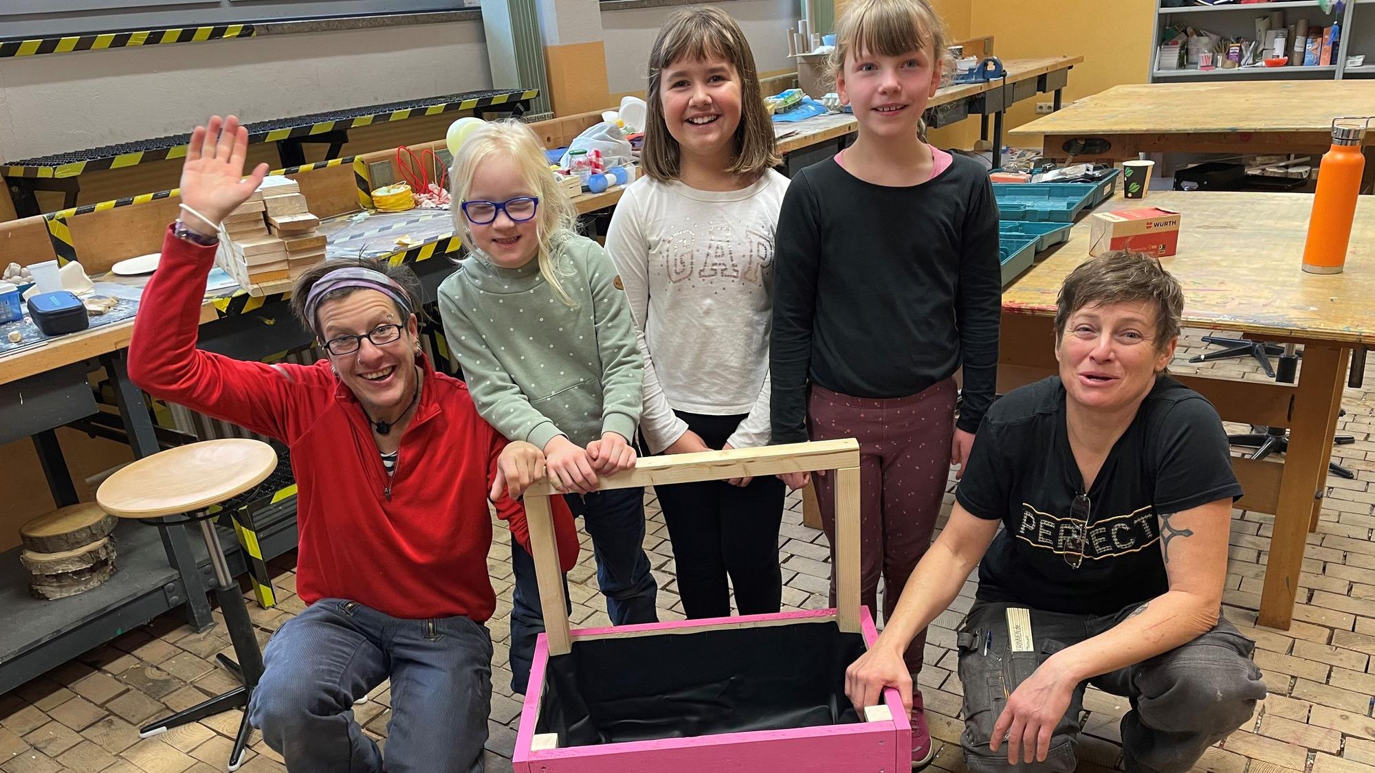 Drei Mädchen und zwei Frauen mit einem selbstgemachten Mini-Hochbeet.