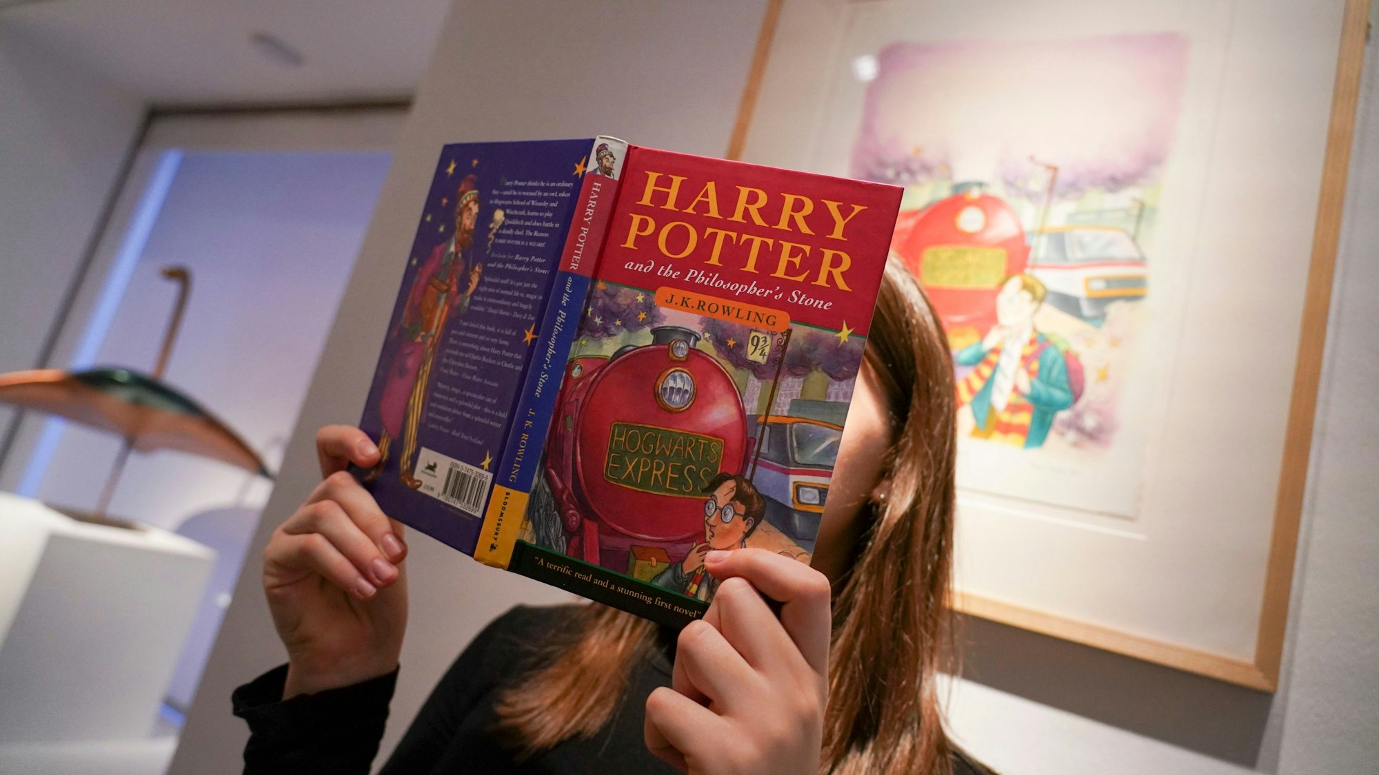 A member of staff holds a first edition of J.K. Rowling's "Harry Potter and the Philosopher's Stone", as it is set to go on auction at Christie's on the Classic Week, for an estimate of £800,000-120,000, in London, Friday, Nov. 29, 2024.(AP Photo/Alberto Pezzali)