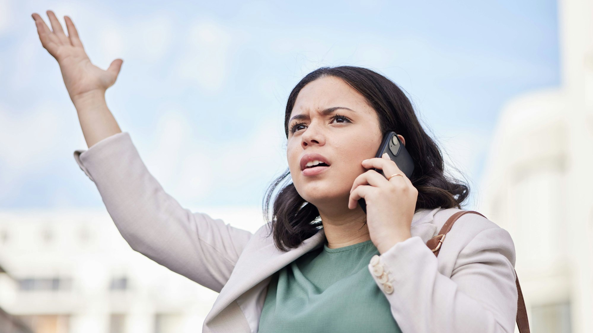 Eine Frau hält ihr Handy an ihr Ohr und blickt empört