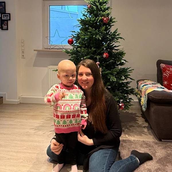 Das Foto zeigt die kleine Juna mit ihrer Mutter vor einem Weihnachtsbaum.