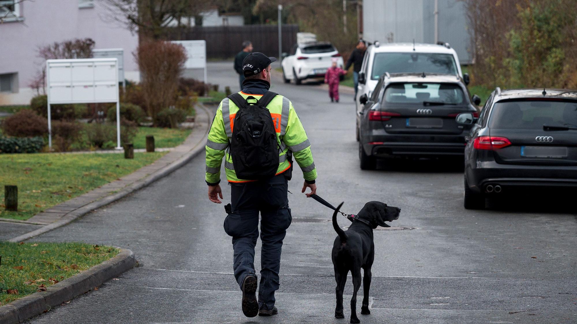 Ein Polizist geht mit einem Personenspürhund durch ein Wohngebiet. (Symbolbild)