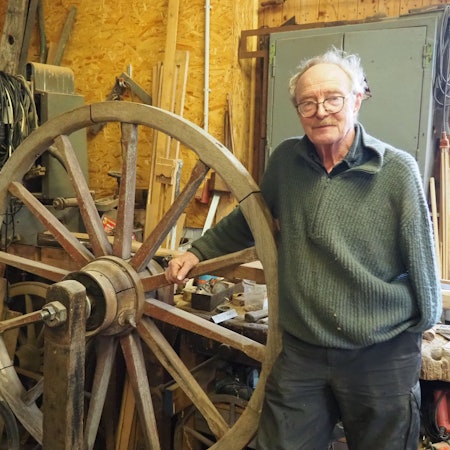 Das Foto zeigt den Stellmacher Walter Keil in seiner Werkstatt mit einem hölzernen Rad.