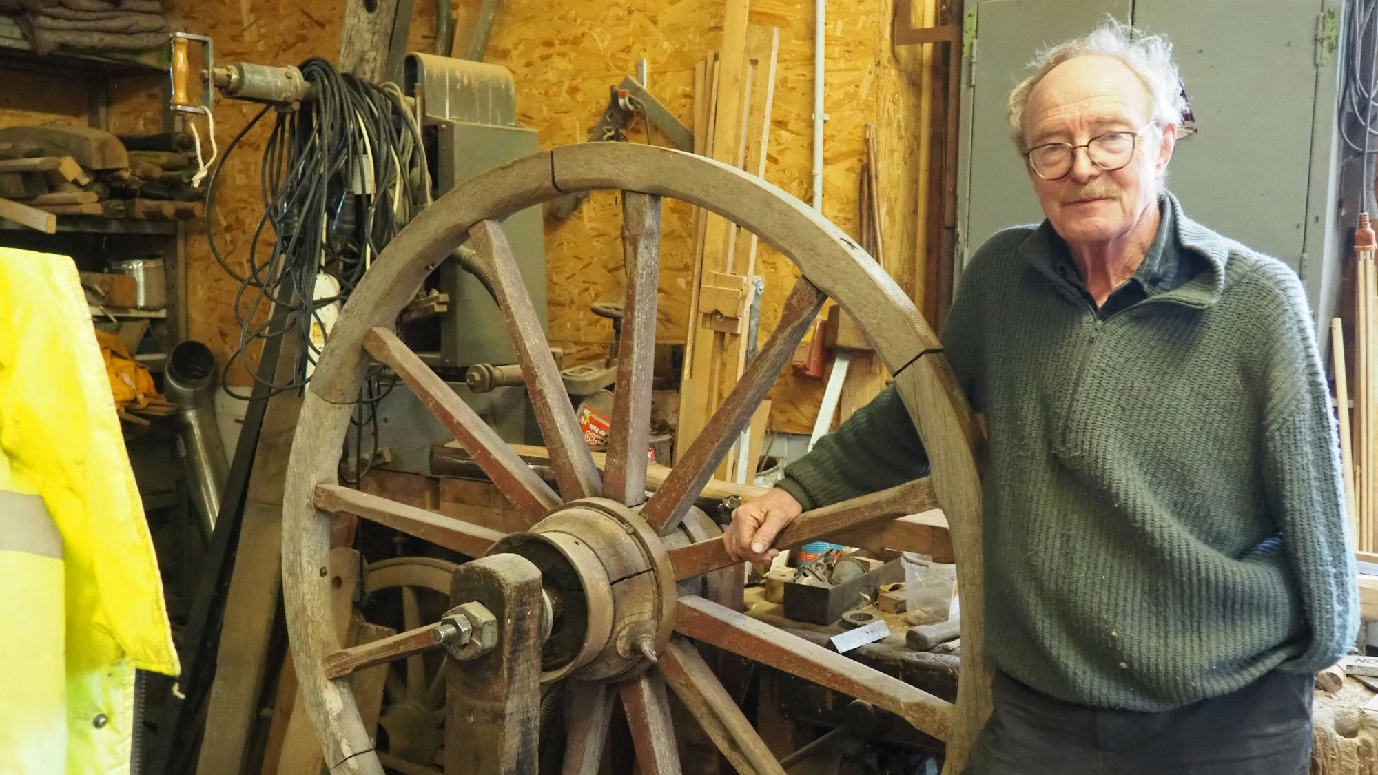 Das Foto zeigt den Stellmacher Walter Keil in seiner Werkstatt mit einem hölzernen Rad.