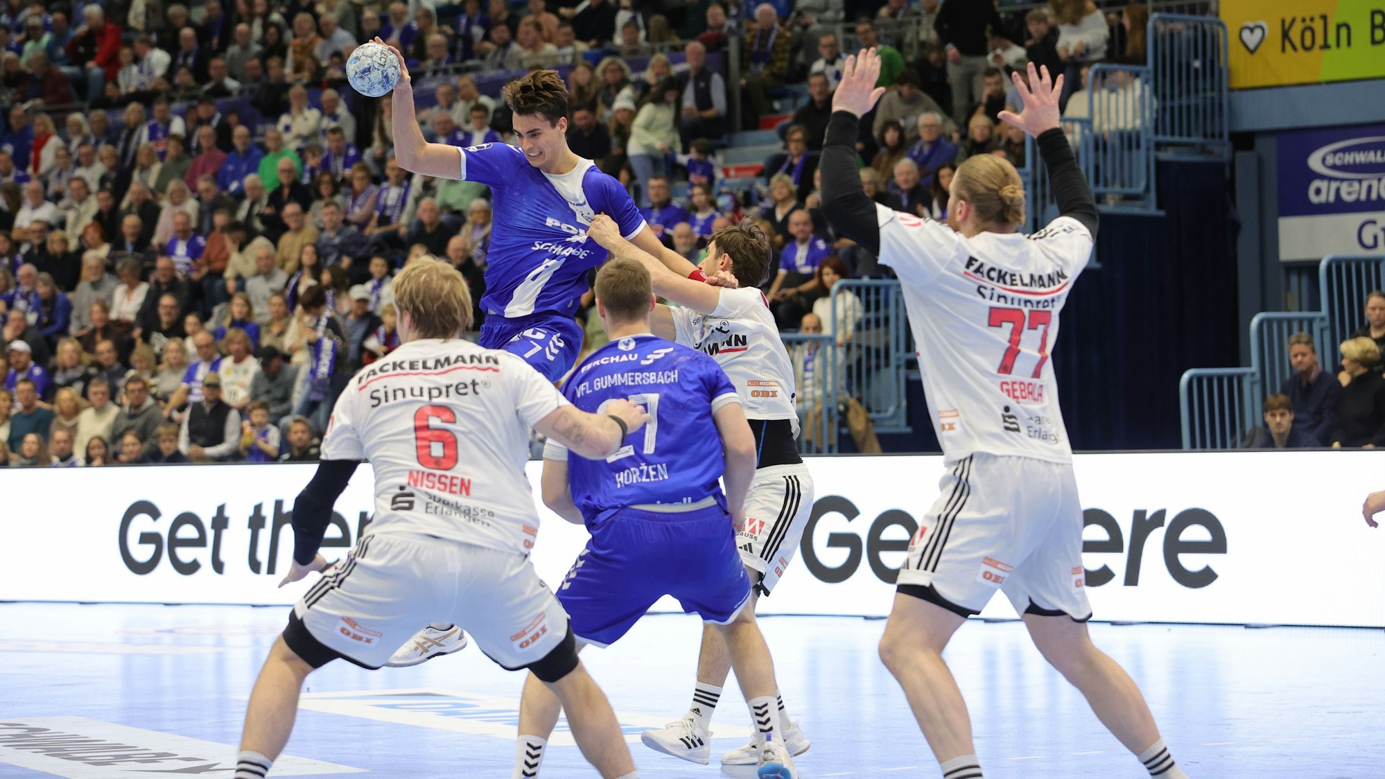 Julian Köster wird beim Sprungwurf von einem Erlanger Abwehrspieler am Trikot gezogen.