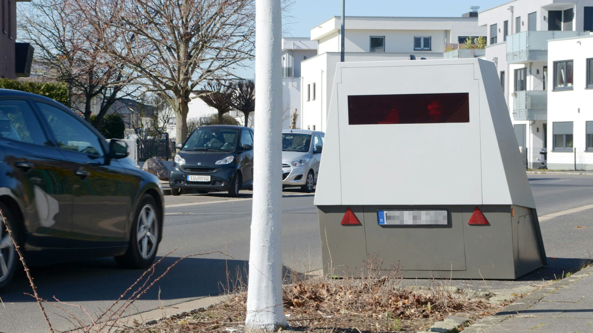 Das Bild zeigt die Messanlage, auf der Straße fährt ein Auto. Im Hintergrund stehen weitere Wagen.