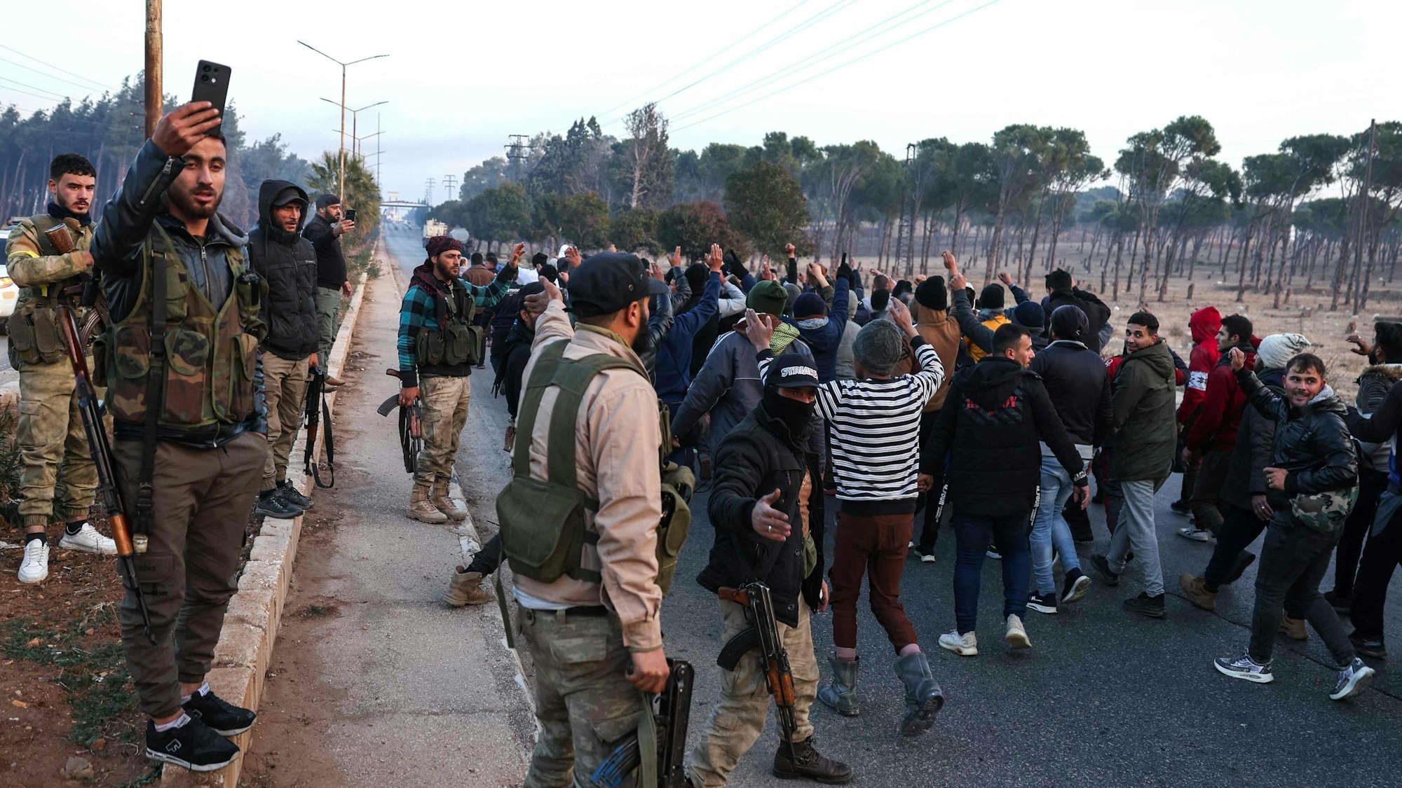 Syrian rebel fighters parade detained pro-government soldiers outside the central city of Homs, after rebel forces entered Syria's third city overnight. Islamist-led rebels declared that they have taken Damascus in a lightning offensive on December 8, sending President Bashar al-Assad fleeing and ending five decades of Baath rule in Syria. (Photo by OMAR HAJ KADOUR / AFP)