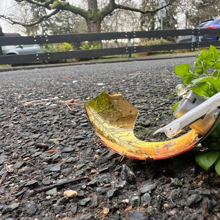 Auf dem Foto ist eine zerbrochene goldene Christbaumkugel zu sehen.
