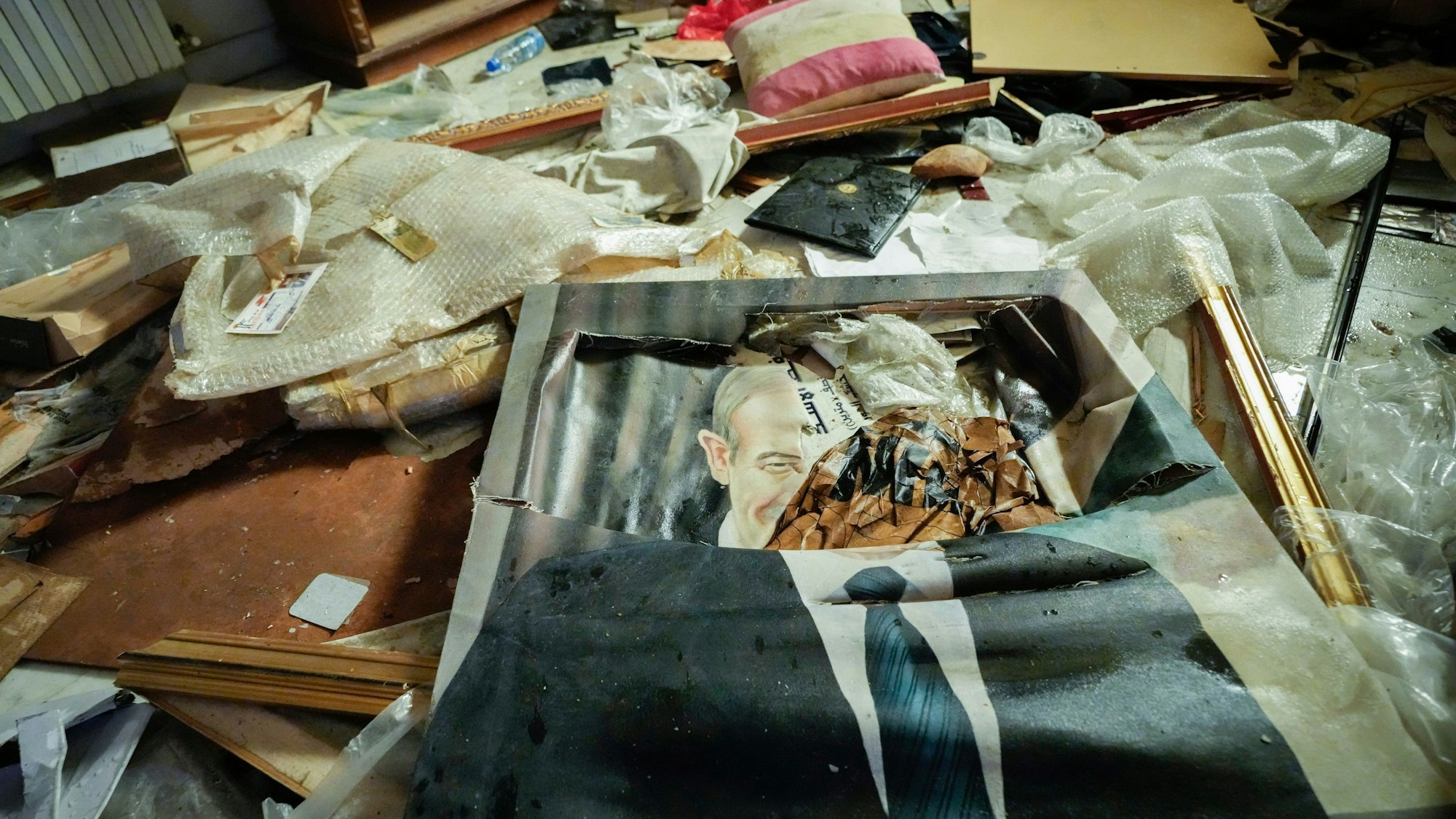 Ein zerbrochenes Porträt des verstorbenen syrischen Präsidenten Hafis al-Assad liegt auf dem Boden, während Menschen in der durchwühlten Privatwohnung des syrischen Präsidenten Bashar Assad im Malkeh-Viertel nach Habseligkeiten suchen.