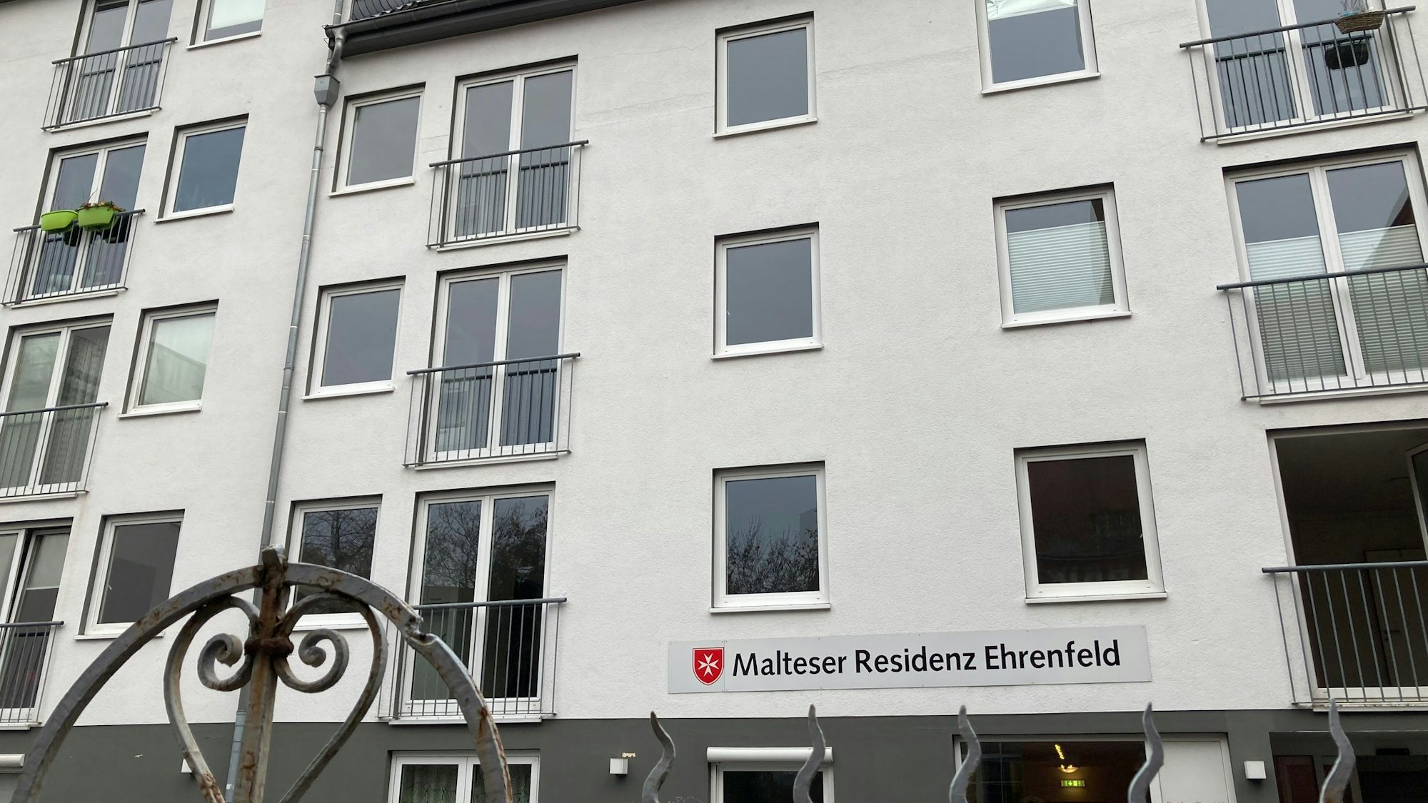 Ein mehrstöckiges Wohngebäude. Über dem Eingang hängt ein Schild mit der Aufschrift Malteser Residenz Ehrenfeld.