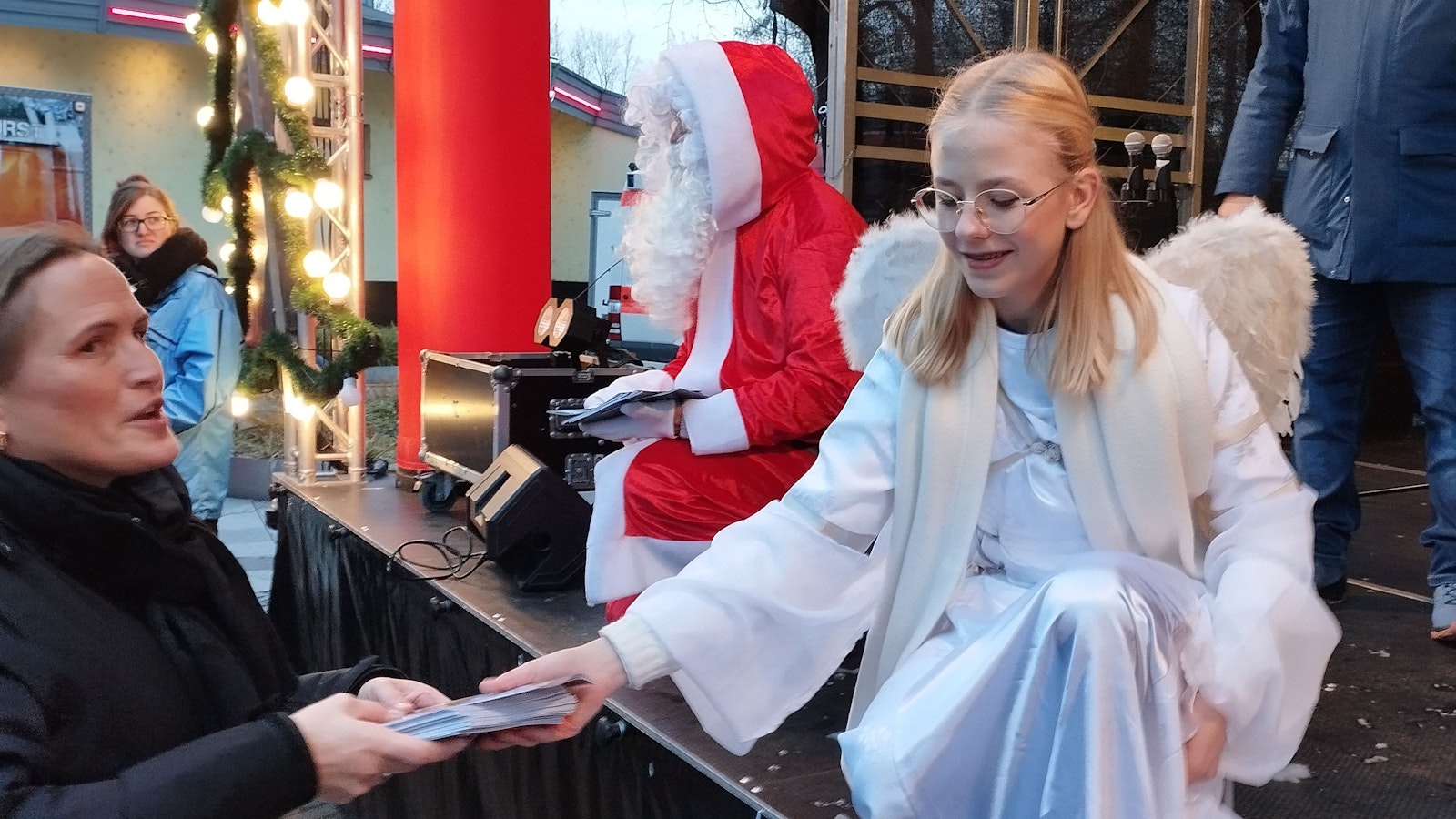 Ein als Engel verkleidetes Mädchen verteilt das Liederheft zum Bergheimer Nikolaussingen.