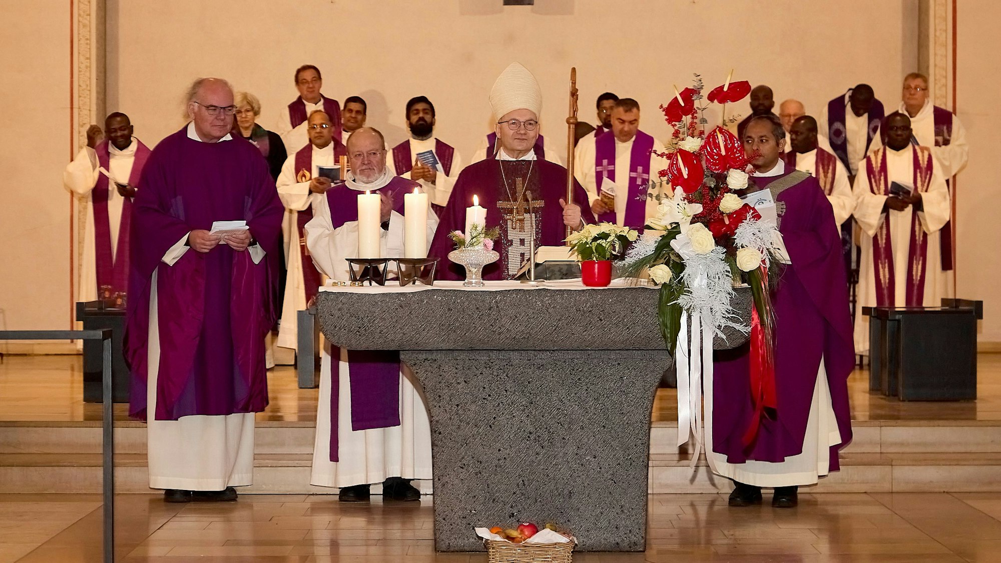 Der Aachener Bischof mit drei Konzelebranten am Altar, vor dem ein Korb mit Obst steht. Im Hintergrund zahlreiche weitere kircheliche Würdenträger.