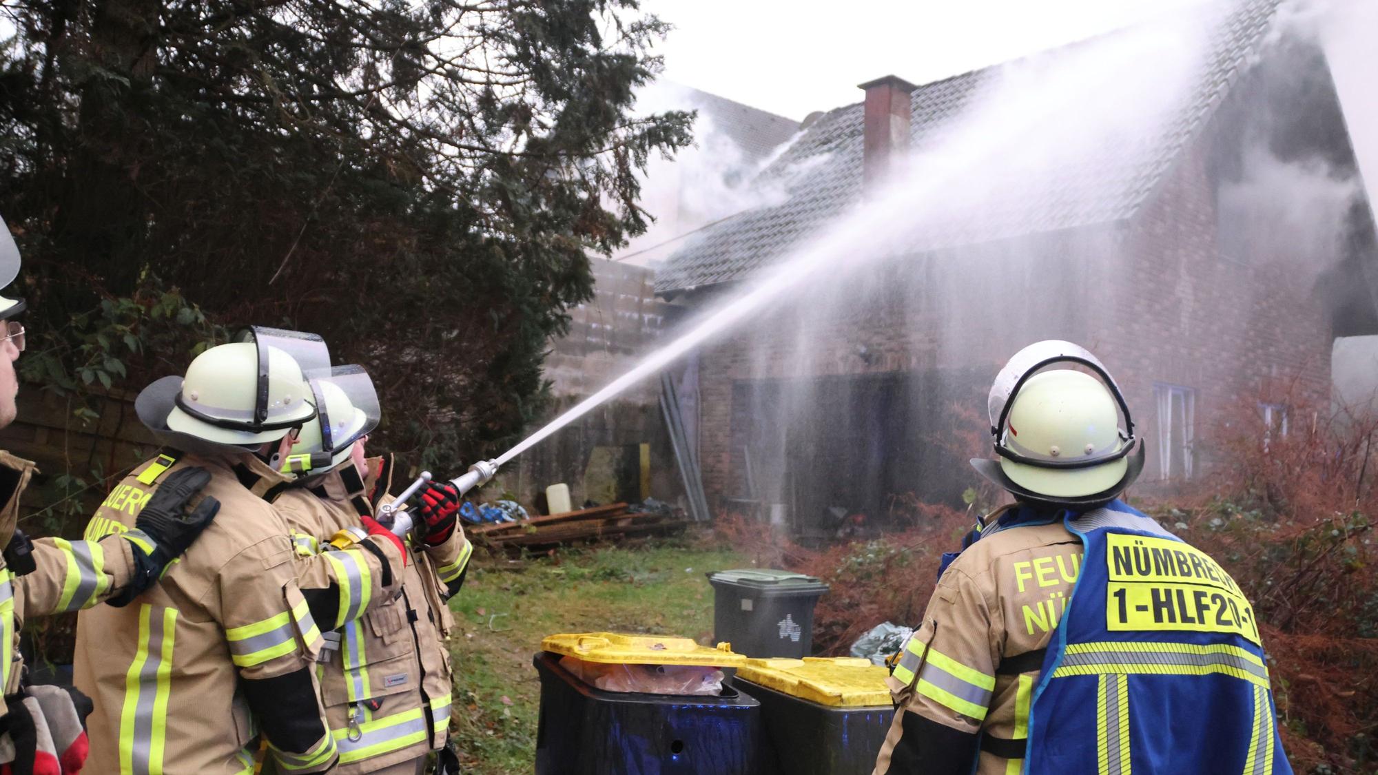 Einsatzkräfte der Feuerwehr löschen einen Wohnhausbrand.