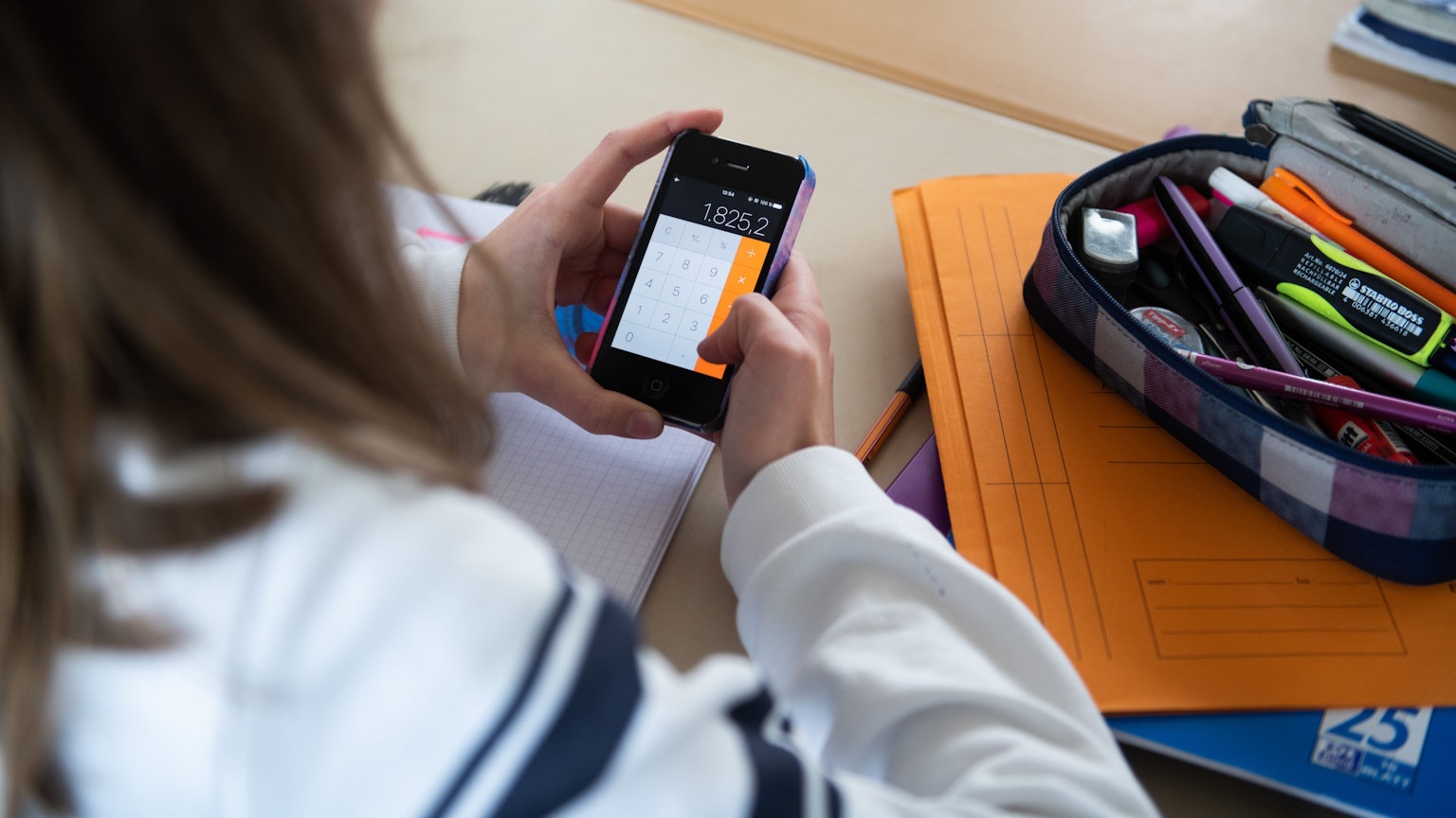 Eine Schülerin einer fünften Klasse eines Gymnasiums benutzt die Rechenfunktion ihres Smartphones.