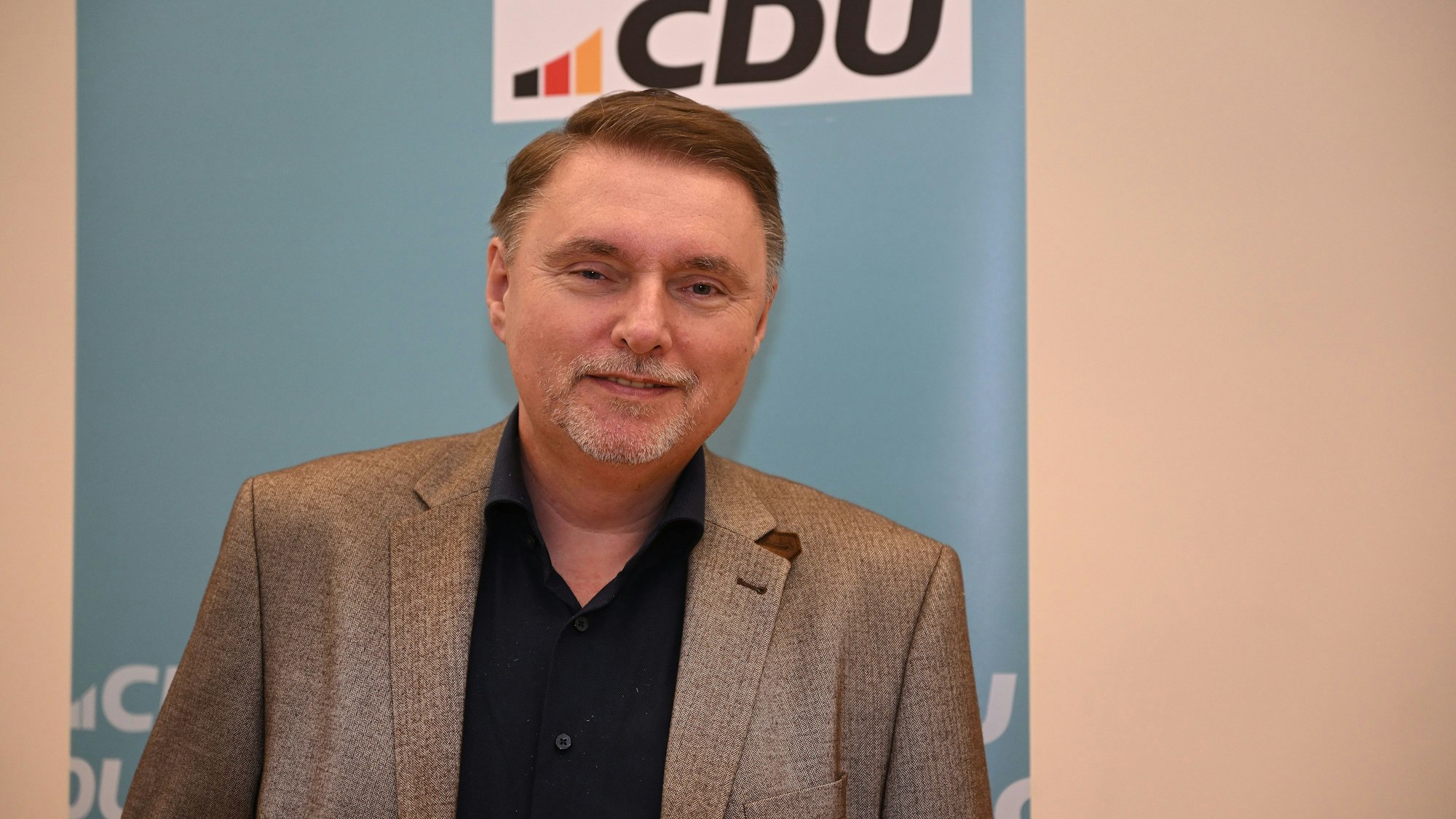 CDU-Bürgermeisterkandidat Michael Eyer steht vor einer CDU-Wand in Overath.