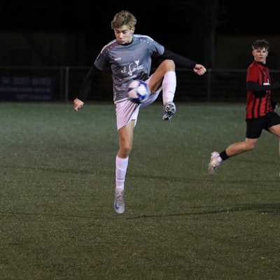 Ein Jugendfußballer stoppt den Ball auf Bauchhöhe mit einem hochgezogenen Bein.