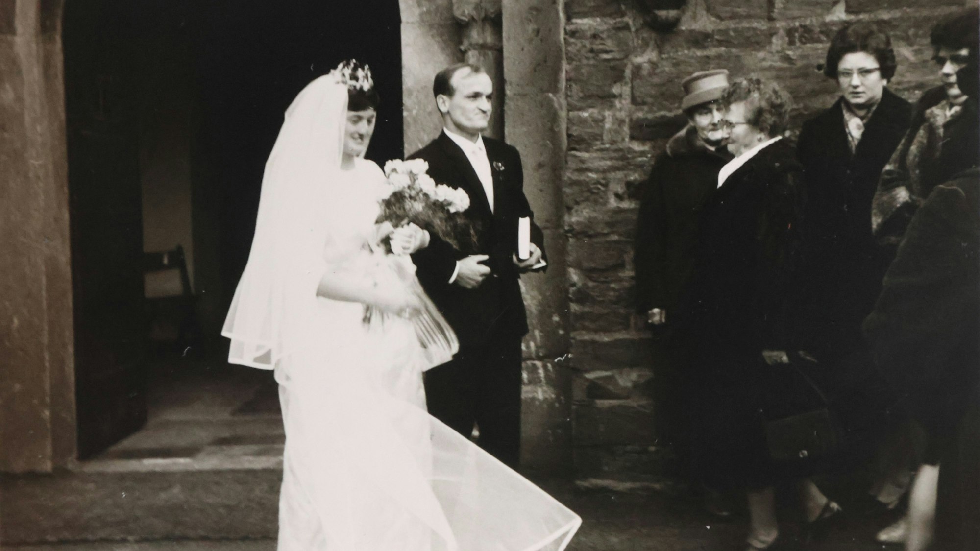 Ein Hochzeitspaar vor der Kirche in Waldbröl. Das Foto ist ein altes schwarz-weißes Foto.