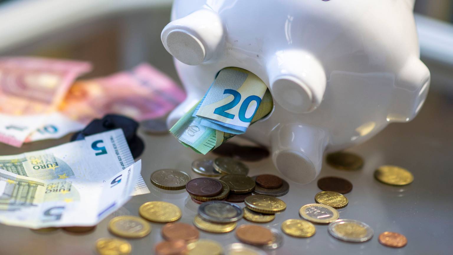 Geld steckt im Bauch eines Sparschweins. Am 30. Oktober ist Weltspartag.