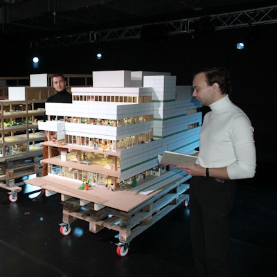 Drei Studenten mit dem Modell eines Kaufhauses.